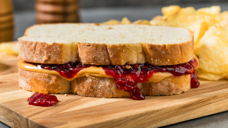 Homemade Peanut Butter and Jelly Sandwich with Chips on a Wooden Board
