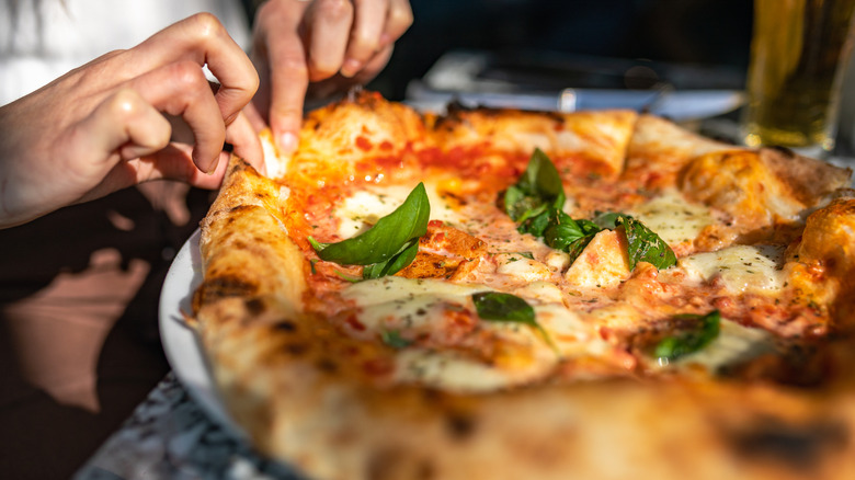 Hands tear away at pizza in a restaurant