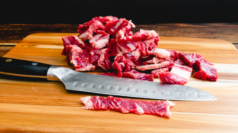 Sliced, raw steak with knife on cutting board