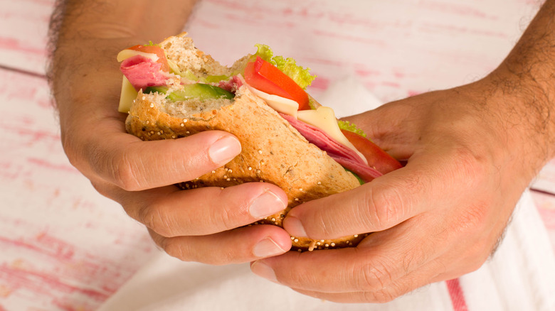 Two hands holding a sub sandwich
