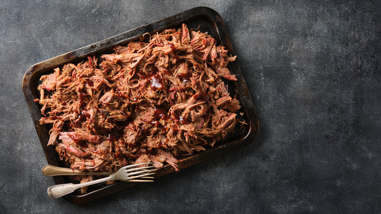 A large tray of pulled pork is photographed from above.