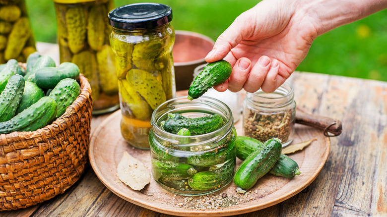 Person picking a pickle from a jar