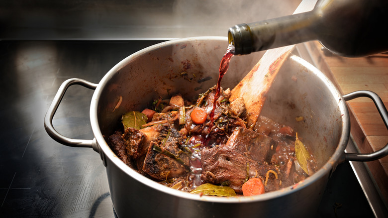 Pouring red wine into a pot roast