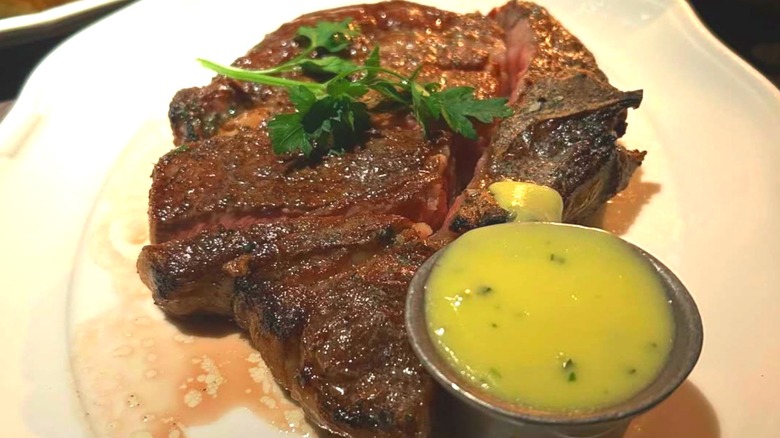 Bavette's juicy ribeye served with béarnaise sauce on the side and fresh garnish on top.
