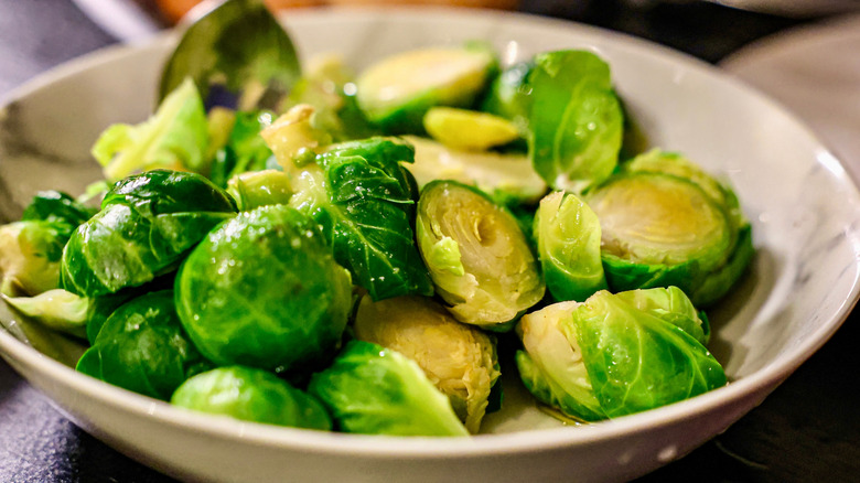 White bowl filled with halved Brussel sprouts.