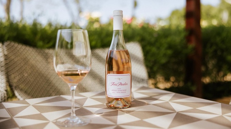 Bottle of Fess Parker Pinot Noir Rosé with glass on a geometric patterned outdoor table.