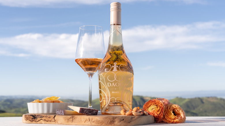 Bottle of DAOU Rosé with glass on a table in front of mountains.