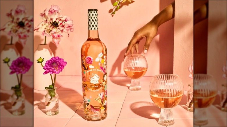 Bottle of Wölffer Rosé with glasses and flowers in a pale pink setting.