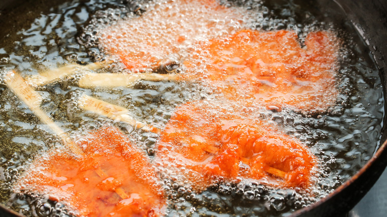 Skewered salmon is frying in oil