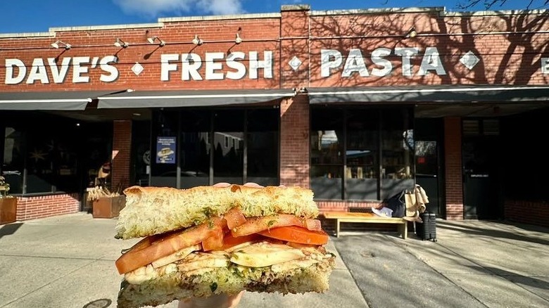 Someone holding a panini in front of Dave's Fresh Pasta