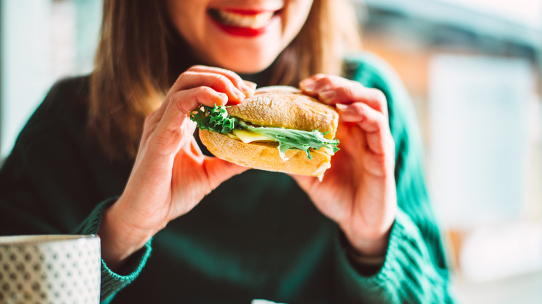 A smiling woman holding a sandwich