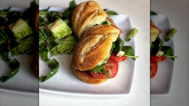 A baguette sandwich and salad on a plate
