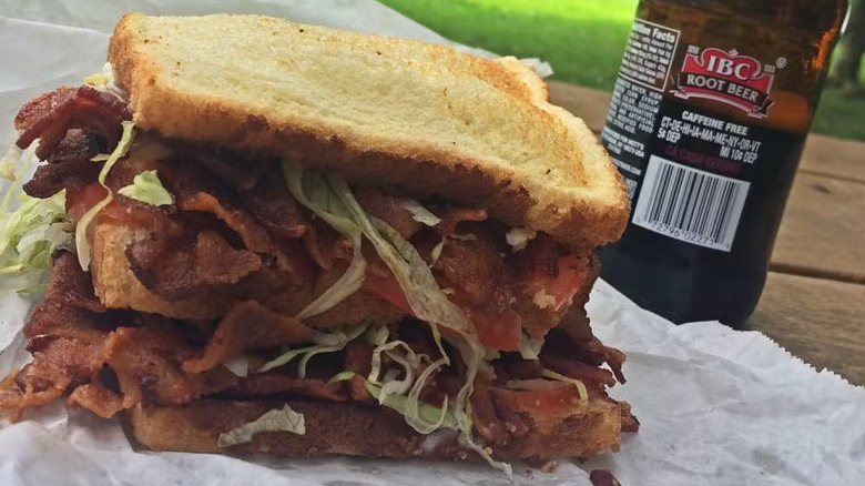 A sandwich and a root beer on a park table