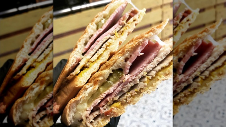 Person holding two halves of Cubano sandwich