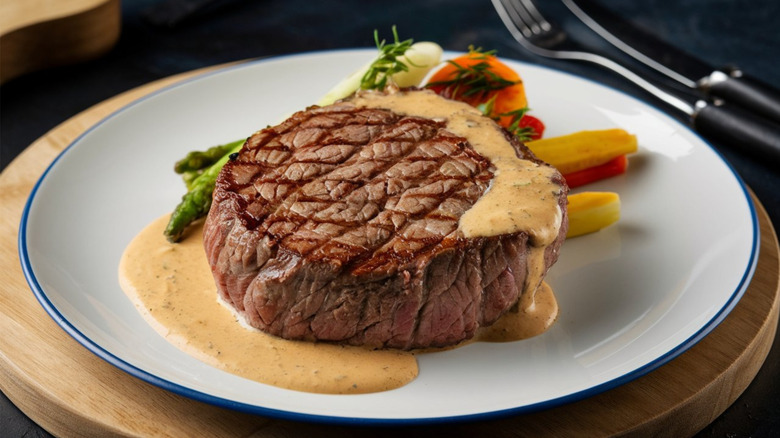steak with Béarnaise sauce on a white plate with vegetables