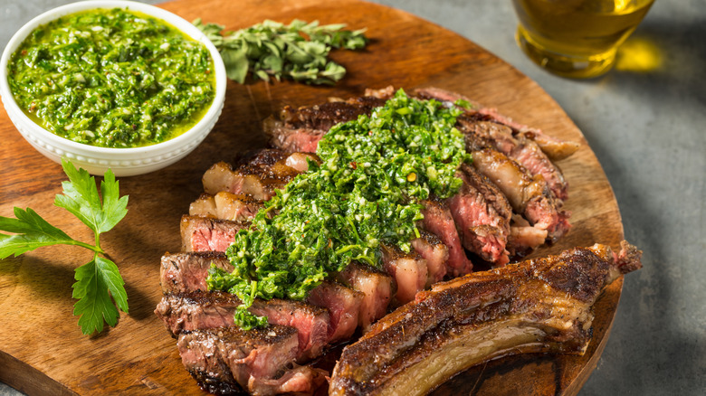 steak with chimichurri sauce on a wood platter