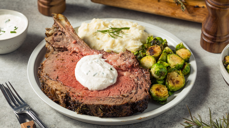steak with horseradish sauce on white plate with mashed potatoes and brussel sprouts