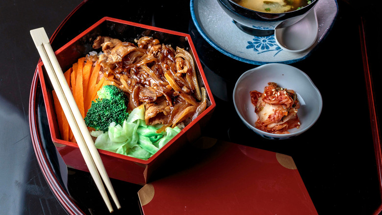 steak with miso ginger sauce in bowl with vegetables and chopsticks