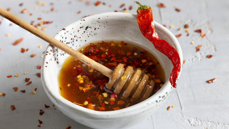 Sweet chili sauce in a white bowl with honey wand