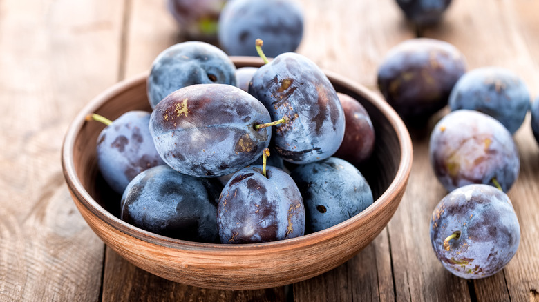 A bowl of plums on a wooden table