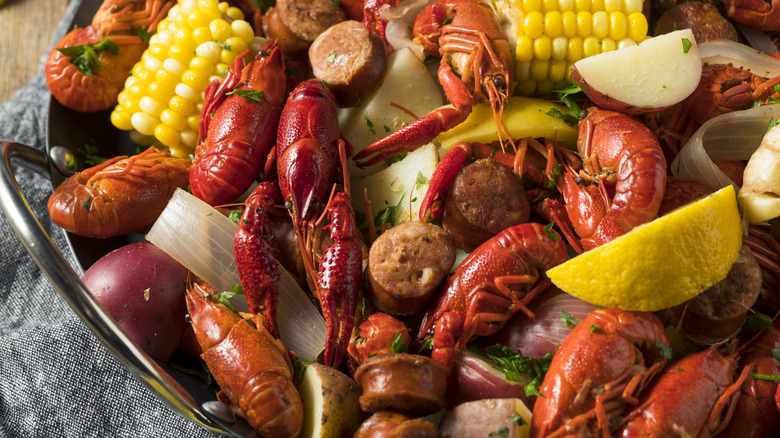 Seafood boil with crawfish, sausage, potatoes, onions, corn, and lemon wedges