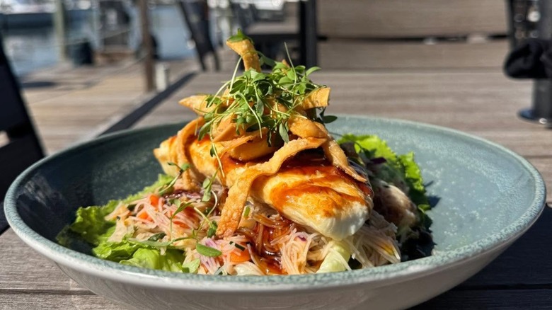 Halibut with wontons and greens on plate outside