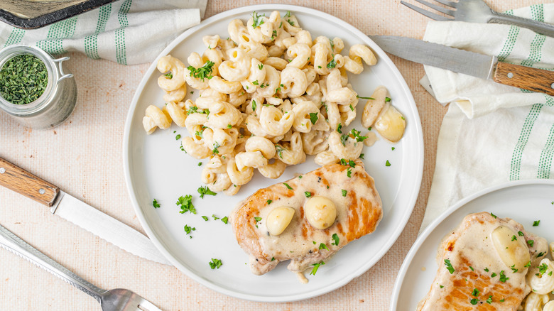 Pork chop on a plate with a side of pasta.