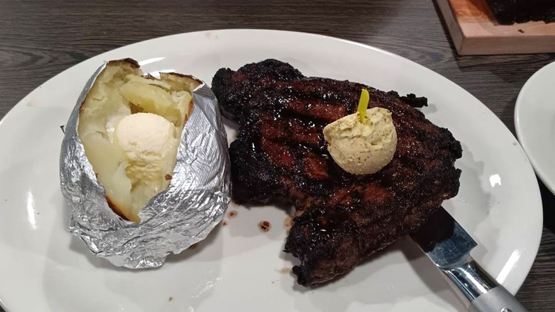 Big Mike's Steakhouse's ribeye with a baked potato served on a white plate.