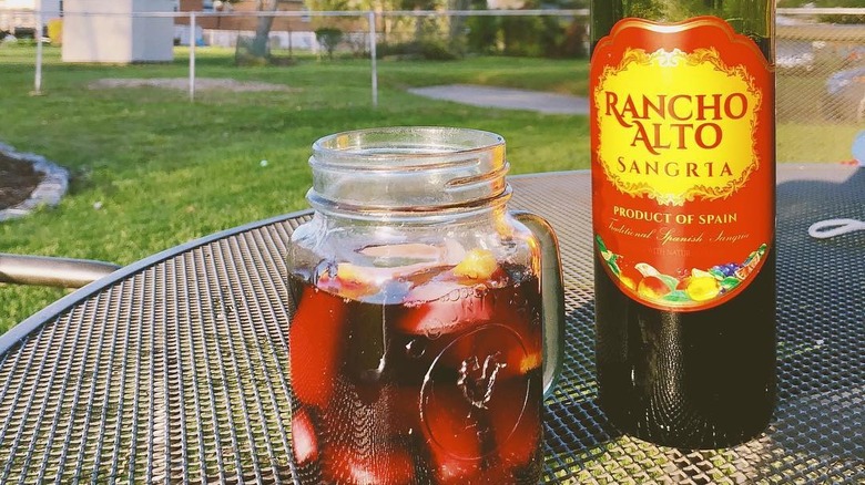 A bottle of Rancho Alto Sangria with a jug in front of it