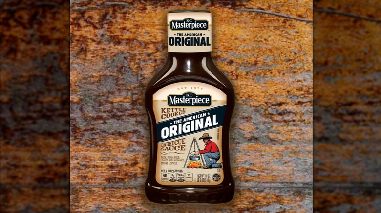 A bottle of KC Masterpiece barbecue sauce on a wooden table