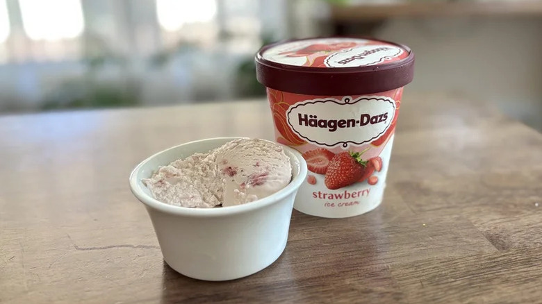 Haagen-Dazs strawberry ice cream carton next to a bowl of strawberry ice cream