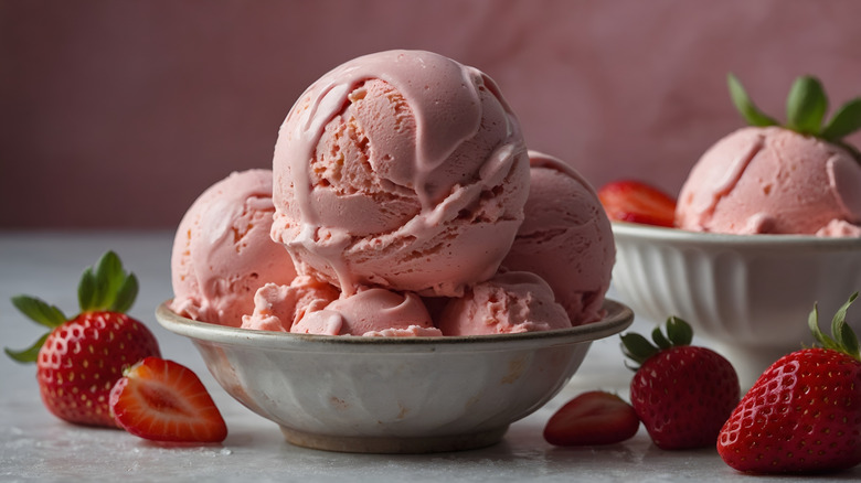 Bowl of strawberry ice cream surrounded by strawberries