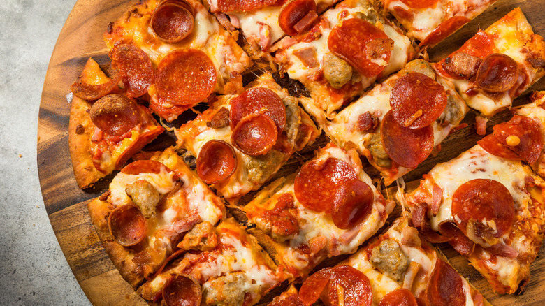 Chicago tavern-style pizza with pepperoni, sausage, and bacon on a wooden pizza peel