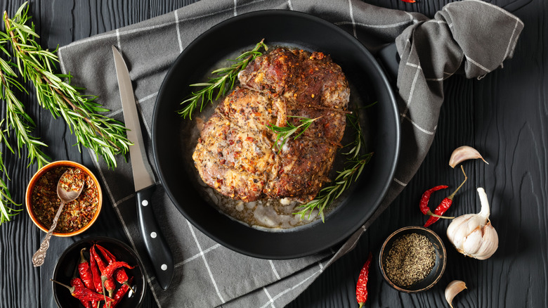 A Boston butt with herbs in a black pan