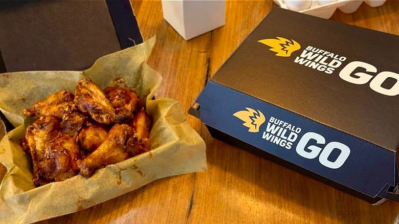 Box of Buffalo Wild Wings open with sauced chicken wings next to closed box.