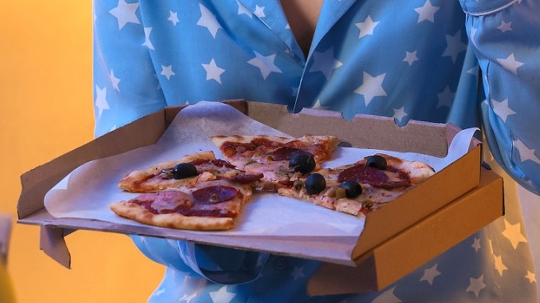 Person in pajamas eating pizza at night.