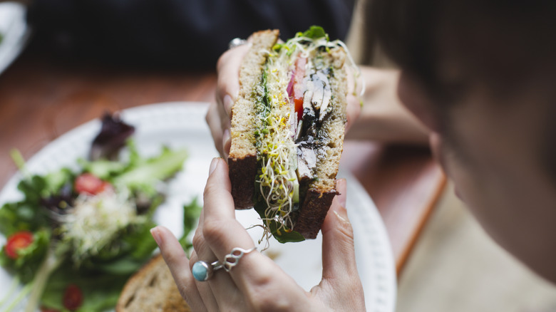 a woman eating a vegan cheese sandwich