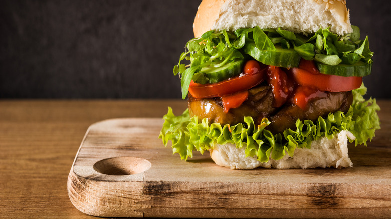 seitan burger with all the fixings on wooden board