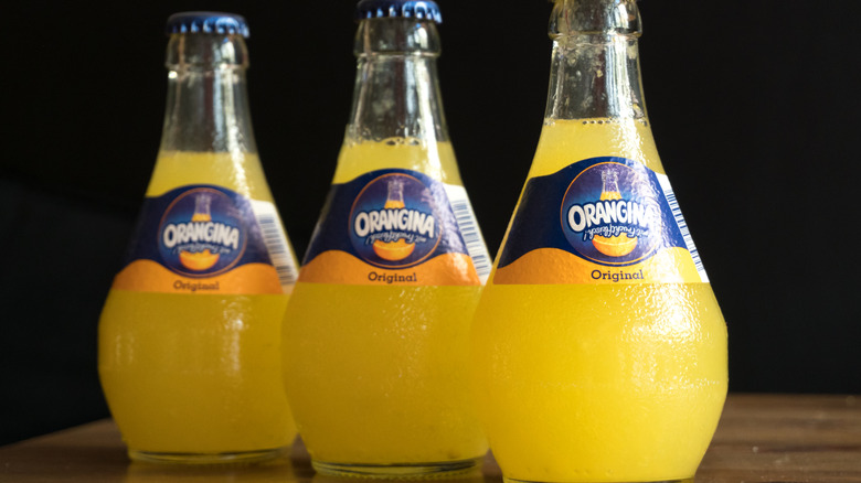 Bottles of Orangina Original flavor lined up in a diagonal row