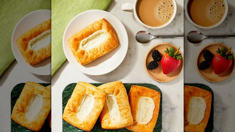 Marketside Cream Cheese Danishes on a plate and a tray next to a cup of coffee, a spoon, and berries in a small wooden dish