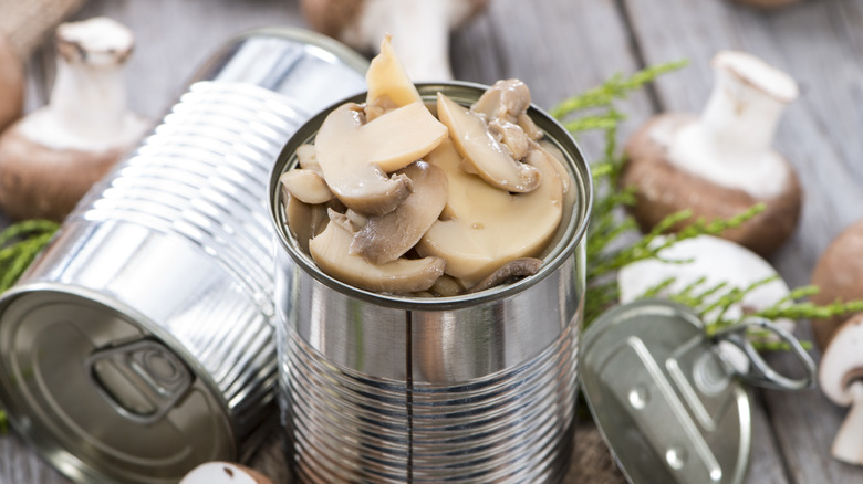 Open cans of sliced mushrooms on a table.