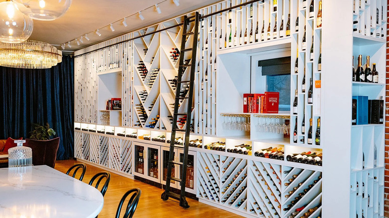 Ladder leans against wall full of wine bottles