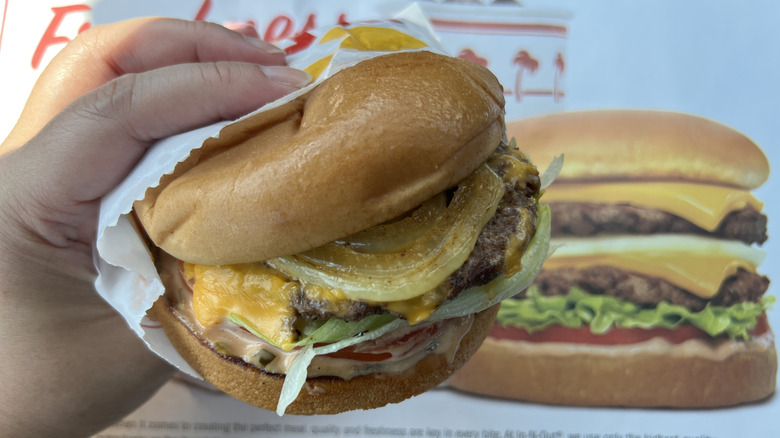 Hand holding In-N-Out burger with grilled onion