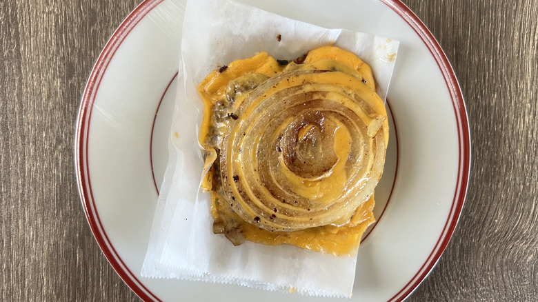 Bunless cheeseburger with grilled onion on white plate