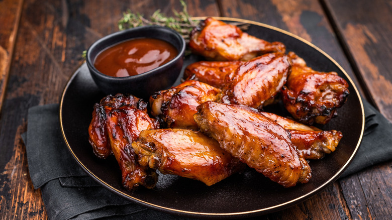 bbq chicken wings on a black plate with dipping sauce