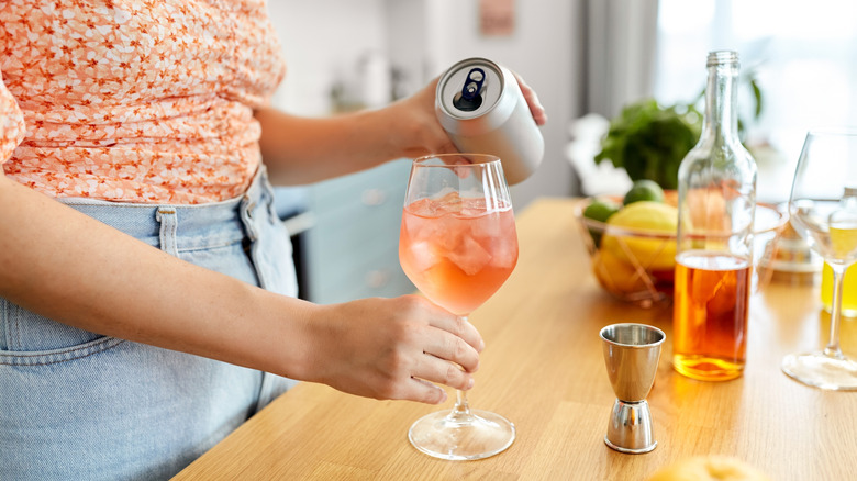 Person pouring canned wine into a glass