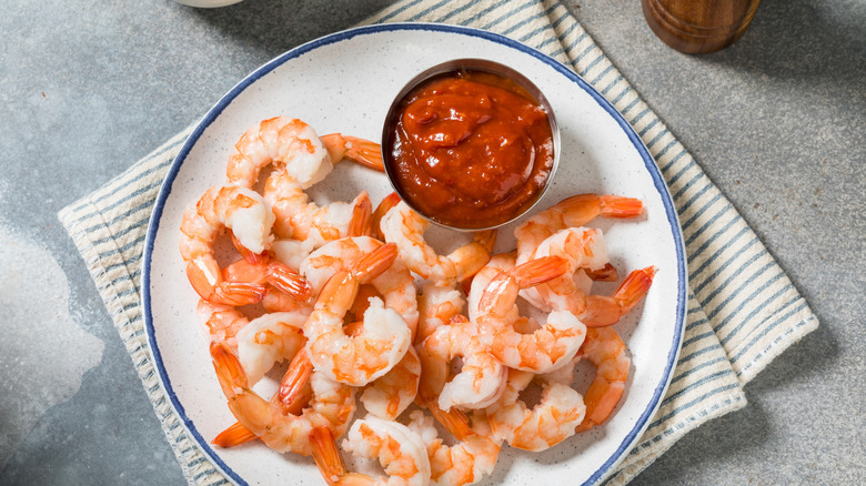 Shrimp cocktail in a plate over a kitchen towel