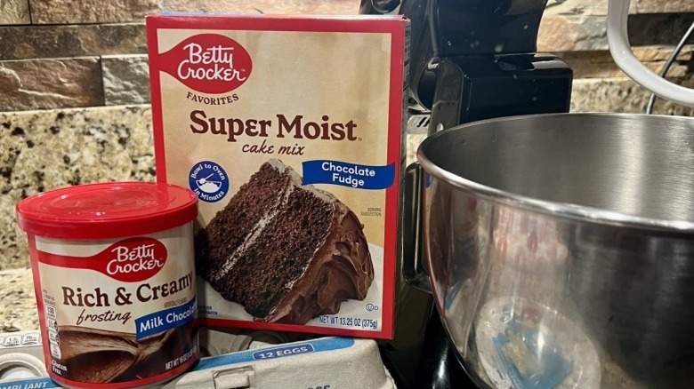Betty Crocker Super Moist cake mix chocolate fudge cake mix besides a metal mixing bowl