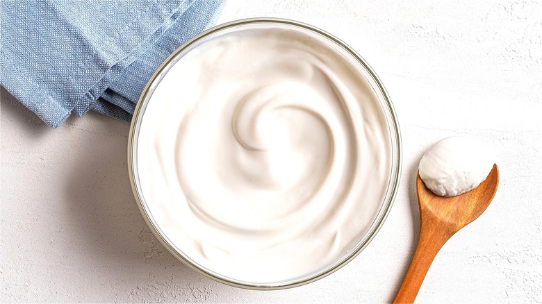 Greek yogurt in clear bowl and on wooden spoon