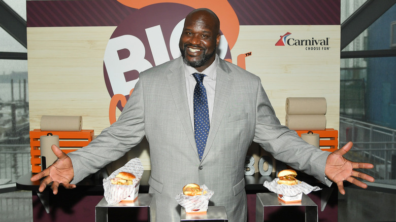 Shaquille O'Neal standing in front of sign with Big Chicken products in front of him on display.